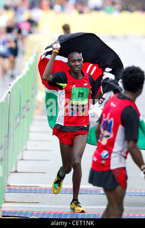 African male runner from  Kenya celebrates win carrying flag from his native country Kenya after winning Austin marathon Stock Photo