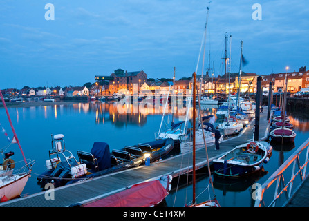 Boats moored alongside a jetty in the quay at Wells-next-the-Sea on the North Norfolk coast at night. Stock Photo