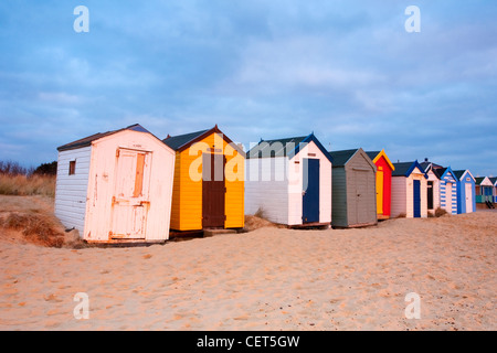 A row of colourful beach huts on the sandy beach at Southwold on the Suffolk Coast at dawn. Stock Photo