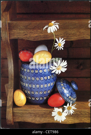 GERMANY - CIRCA 1989: Easter postcard printed in the GDR shows a wooden shelf, Easter eggs, flowers and a jug, circa 1989 Stock Photo