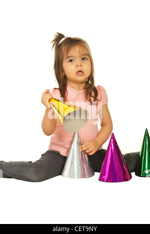 Toddler girl playing with colorful party hats isolated on white background Stock Photo