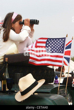 Girl with binoculars watching car races at Goodwood Revival. Stock Photo