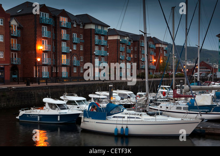 UK, Wales, Swansea, Maritime Quarter, yachts moored in marina beside waterfront apartments at night Stock Photo