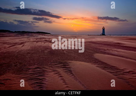 A view from a windswept beach to Talacre Lighthouse at sunset. Stock Photo