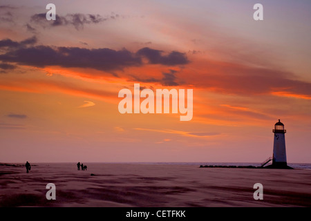 A view from a windswept beach to Talacre Lighthouse at sunset. Stock Photo