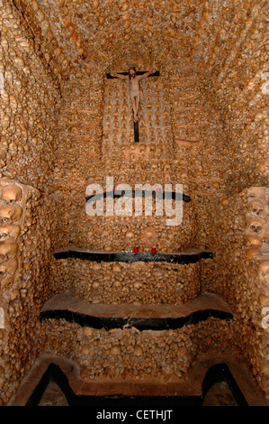 The figure of a crucified Christ dated from the 16th century inside Capela dos Ossos Bones Chapel constructed completely of approximately 1500 skulls and bones, arranged in lateral bands and surmounted by a Romanesque arch on the southern side of the 16th century Nossa Senhora da Conceiçao Parish Church, located on the historical centre of Alcantarilha village in Algarve region Portugal Stock Photo