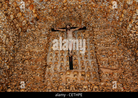 The figure of a crucified Christ dated from the 16th century inside Capela dos Ossos Bones Chapel constructed completely of approximately 1500 skulls and bones, arranged in lateral bands and surmounted by a Romanesque arch on the southern side of the 16th century Nossa Senhora da Conceiçao Parish Church, located on the historical centre of Alcantarilha village in Algarve region Portugal Stock Photo