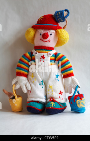 knitted doll, knitted toy - decorator with pots of paint and pot of leaking glue on hat isolated on white background Stock Photo