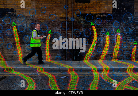 traffic warden walking past pavement art in london, uk Stock Photo
