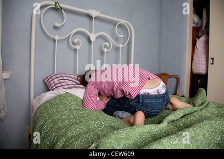 Girl feeling sad curled up on her bed Stock Photo