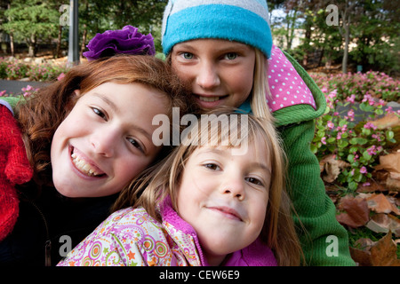 Portrait of three school age girls dressed in winter coats smiling Stock Photo