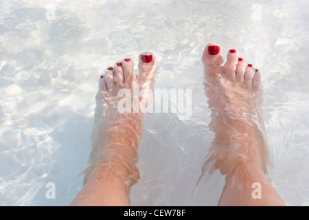 Feet in water with red toenail polish Stock Photo