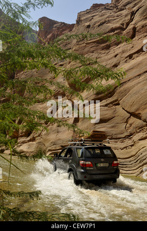 4x4 suv driving through a river in desert gorge. Stock Photo