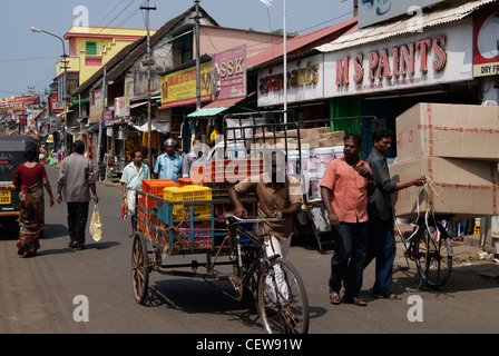 Load carrying cycle rickshaw pulling man through the market rushy streets of Kerala,India.Market scenes of Chalai Bazaar India Stock Photo