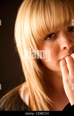 a sad tearful crying upset , blonde haired teenage girl woman biting her fingernails Stock Photo