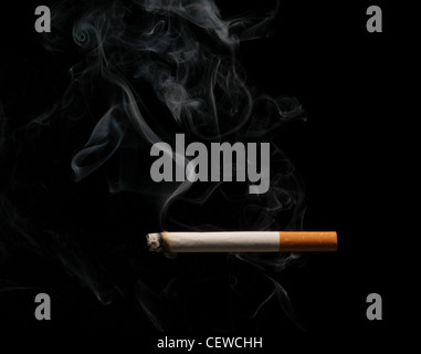 A burning and smoking cigarette on a black background Stock Photo