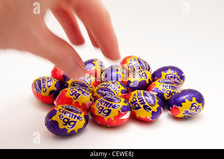 A hand moving in to choose a mini Cadbury creme egg Stock Photo