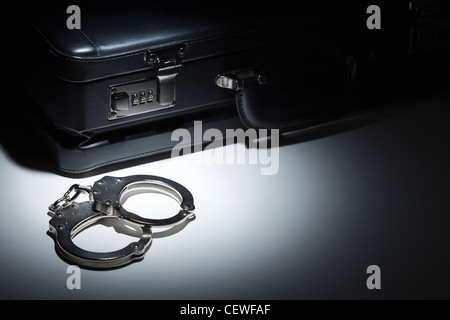 Pair of Handcuffs and Briefcase Under Spot Light Abstract. Stock Photo
