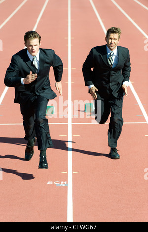 Businessmen racing each other on running track Stock Photo