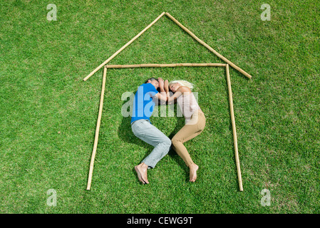 Couple lying on grass within outline of house, high angle view Stock Photo