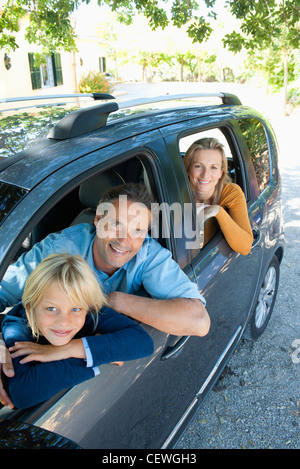 Family together in car, leaning out windows and smiling at camera Stock Photo