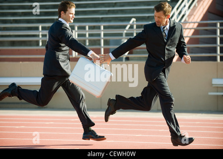Businessmen handing off briefcase in relay race Stock Photo