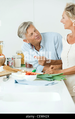 Mature couple preparing food together in kitchen Stock Photo