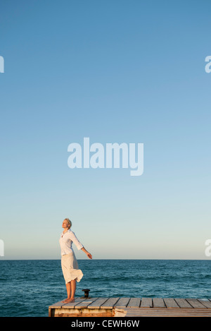 Young woman standing on pier with eyes closed Stock Photo