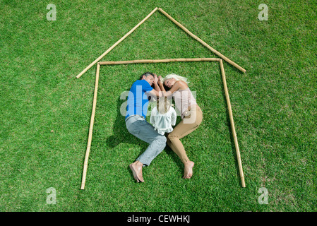 Little girl awake, parents sleeping, together within outline of house, high angle view Stock Photo