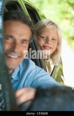 Boy riding in car with father, leaning out window and smiling at camera Stock Photo
