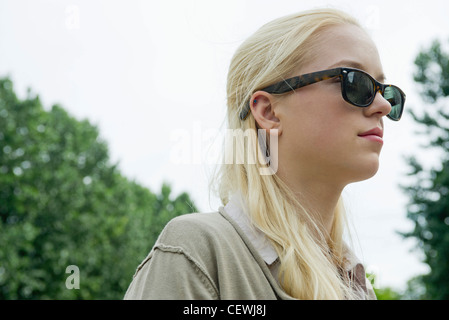 Young woman wearing sunglasses, looking away in thought Stock Photo