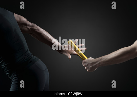 Mid section of hand passing a baton against sports field in background  Stock Photo | Adobe Stock