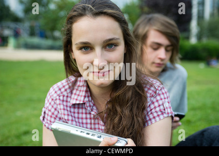 Young woman sitting outdoors, holding laptop computer, portrait Stock Photo