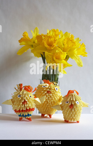 Family of Easter Origami chicks with vase of daffodils isolated on white background Stock Photo