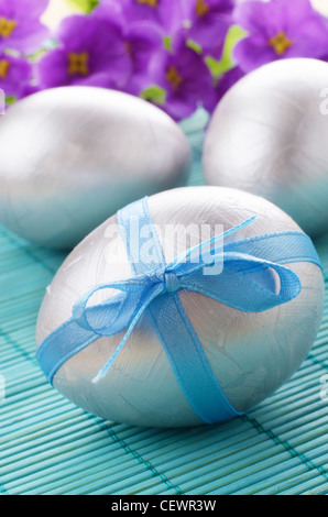Silver Easter eggs with bows over violet background Stock Photo