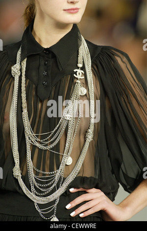 Chanel Paris Ready to Wear S S Close up of female model wearing a sheer black gathered blouse a button up collar and ropes of Stock Photo