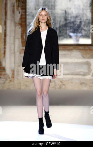 Anna Molinari Milan Ready to Wear Spring Summer Black jacket over white top and ra ra skirt with ankle socks and shoe boots Stock Photo