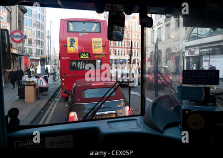 Car in bus lane behind number 243 red double-decker bus in traffic in High Holborn from inside another bus in London UK  KATHY DEWITT Stock Photo