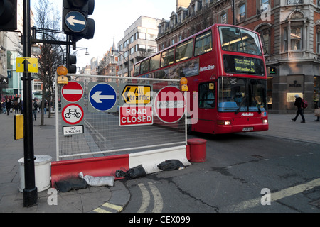 Traffic control signs on a closed section of Oxford Street and a red double-decker bus West End London England UK Stock Photo