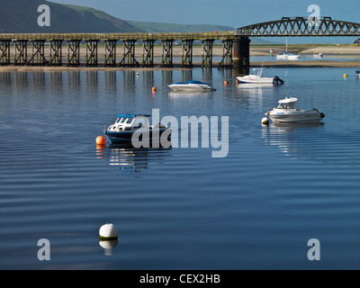 Small boats in Barmouth Harbour by Barmouth Bridge (Pont Abermaw), a single track railway and foot viaduct opened in 1867 across Stock Photo