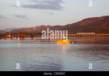 Barmouth harbour and railway bridge - a train is crossing the bridge. Stock Photo