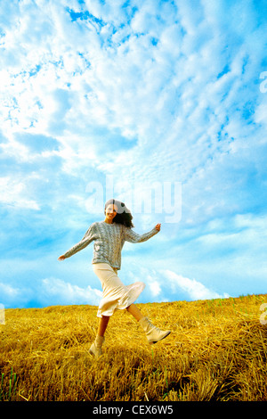 Female walking in field kicking leg up in front of her Stock Photo