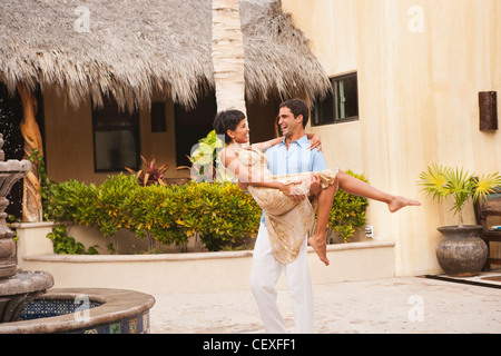 Hispanic man carrying wife in courtyard Stock Photo