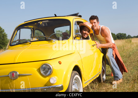 Man pushing girlfriend in broken down car Stock Photo