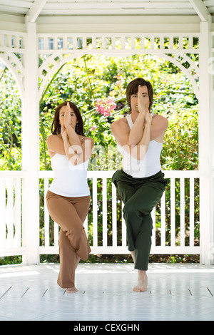 Couple doing yoga in gazebo Stock Photo