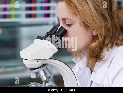 Female researcher looking through a microscope in a laboratory. Stock Photo