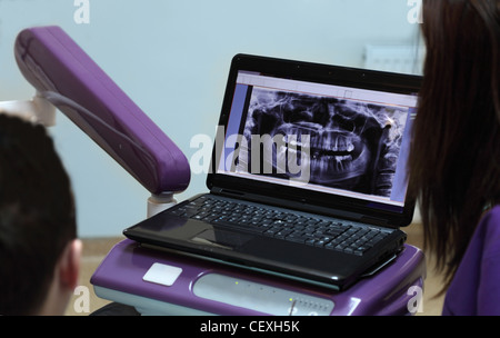 Image of a dentist and her patient looking to a X-ray on a laptop in the dentist office. Stock Photo