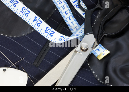 Still life photo of the inside of a bespoke suit jacket with hand stitching and scissors, tape measure, chalk and pins. Stock Photo