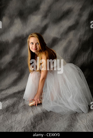 Lovely young modern ballerina tying ballet slippers and getting ready to perform her traditional classical dancing performance. Stock Photo