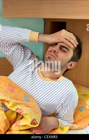 Young man waking up and having terrible headache because of the alcohol he was drinking last night Stock Photo